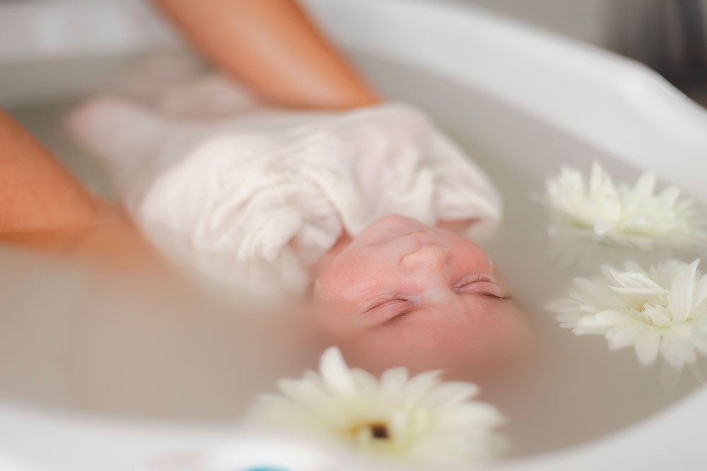 bébé dans un bain enveloppé avec fleurs blanches  lisa mazeau photographe professionnelle gironde