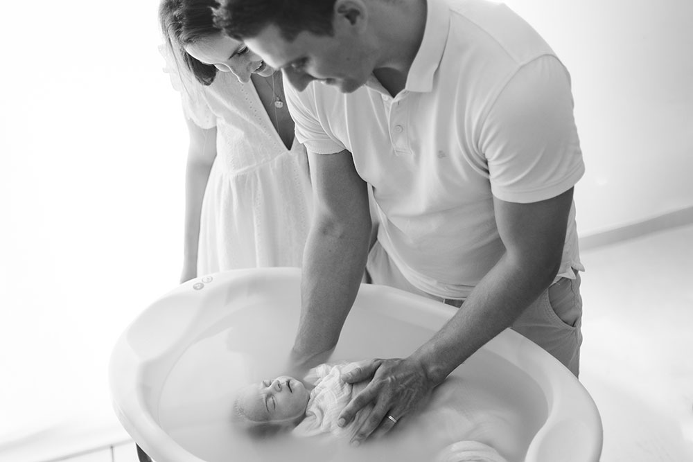 couple sourire avec son bébé dans un bain enveloppé lisa mazeau photographe professionnelle gironde