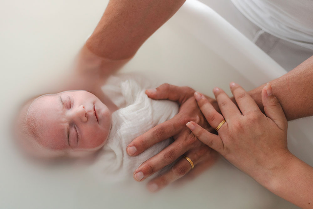 mains parents avec leur bébé dans un bain enveloppé lisa mazeau photographe professionnelle gironde