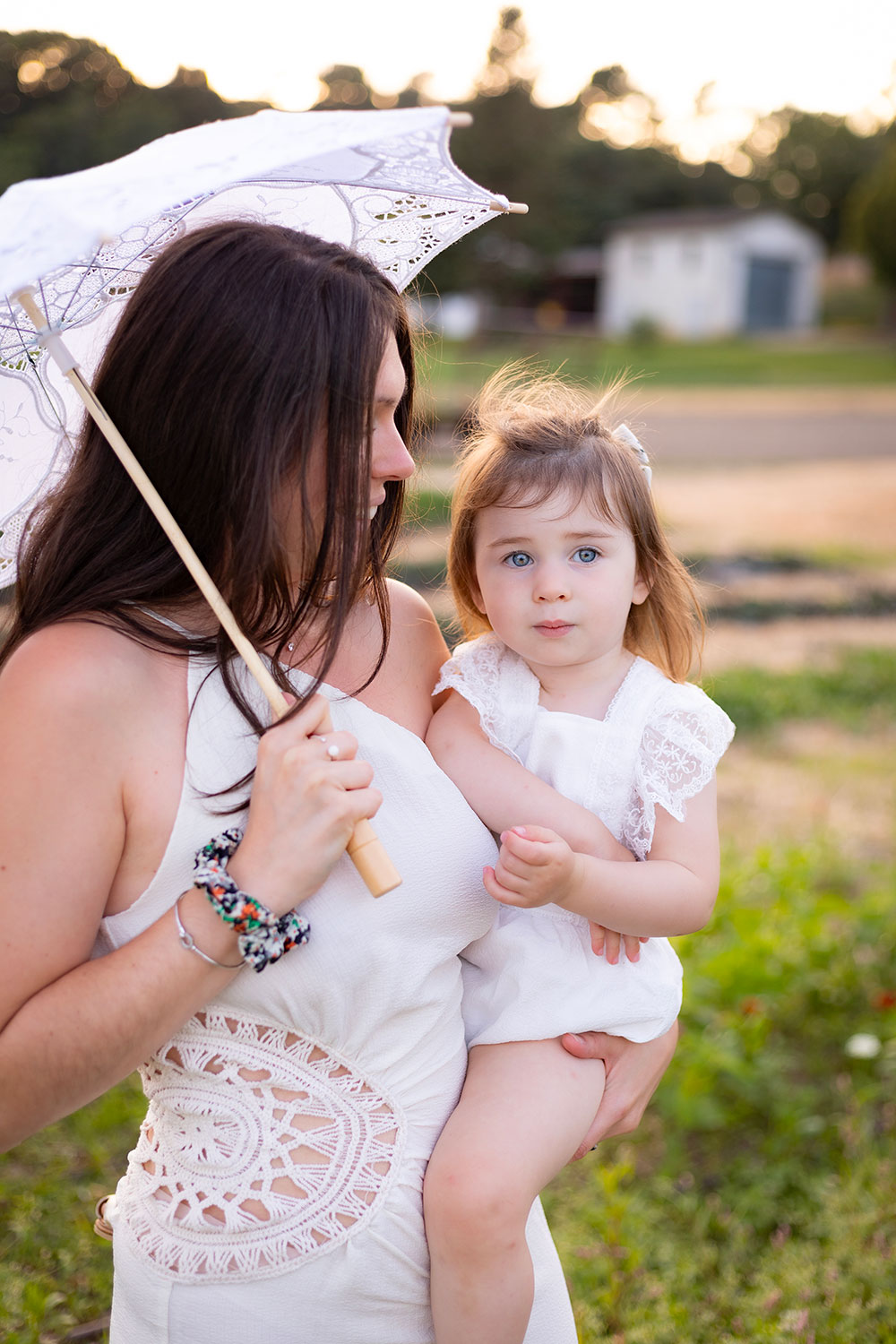 maman avec une ombrelle et une robe dentelle qui porte sa fille lisa mazeau photographe professionnelle gironde