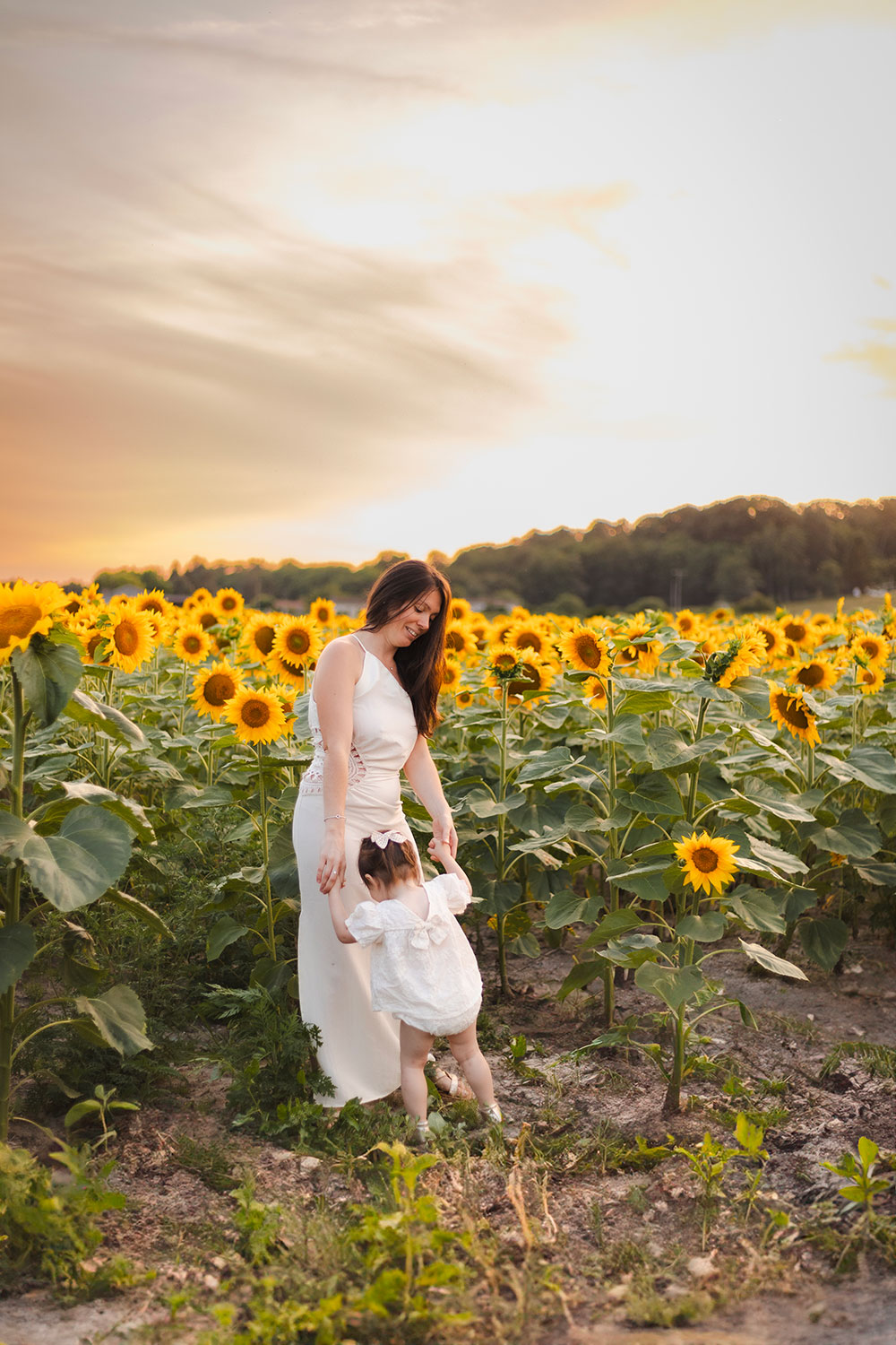 femme et enfant qui se tiennent la main devant tournesol lisa mazeau photographe professionnelle gironde