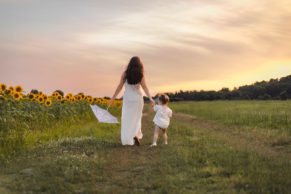 maman et enfant de dos qui marche avec ombrelle a cote des tournesols lisa mazeau photographe professionnelle gironde