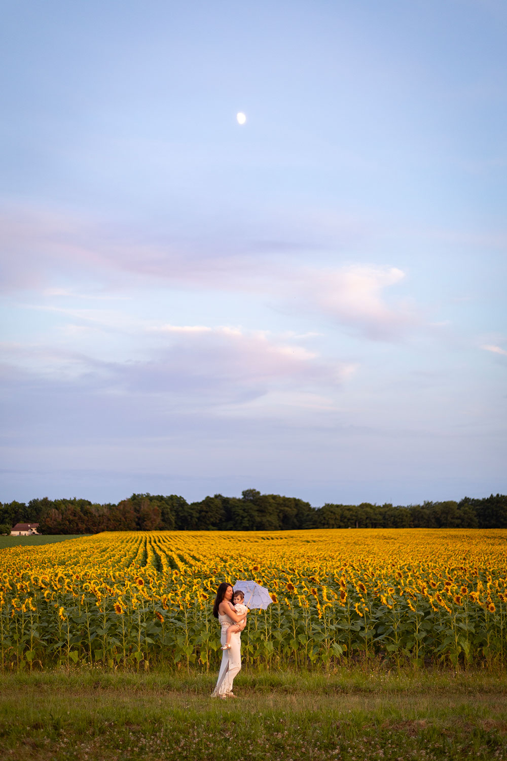 maman et enfant devant un champ de tournesol ciel bleu et lune lisa mazeau photographe professionnelle gironde