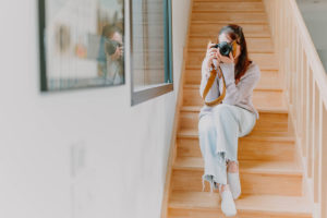 photo de la photographe lisa mazeau en train de prendre une photo avec son appareil assise dans un escalier